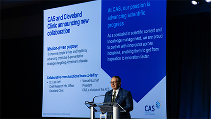 A man at a lectern with a slide about collaboration between CAS and Cleveland Clinic